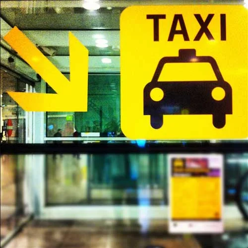 Taxi Arras pour les aéroports de Lille, Paris, Beauvais, etc... Panneau jaune « Taxi » avec une flèche et un pictogramme de voiture.