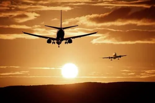 Transfert aéroport Arras avec 1 Taxi SVP à Arras Avions en approche sous un ciel orangé au coucher du soleil.